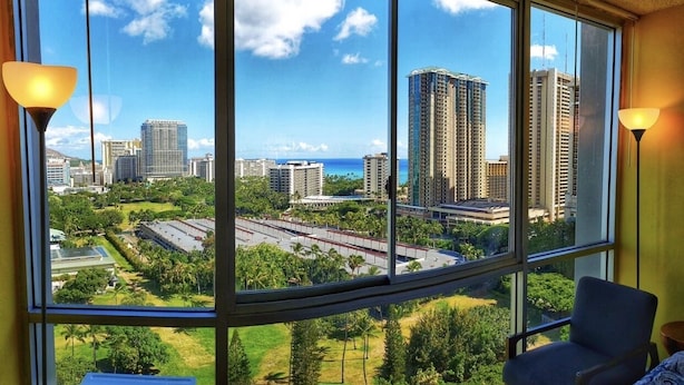 Ein Zimmer mit einem großen Fenster und Blick auf Stadt und Grünflächen.