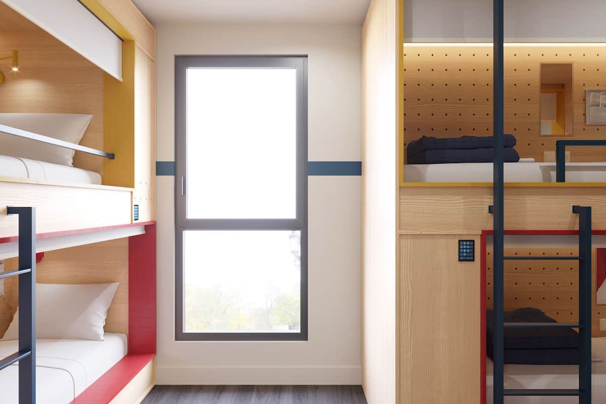 Ein kleines Zimmer mit Etagenbetten, einem Fenster und einer Küchenzeile.