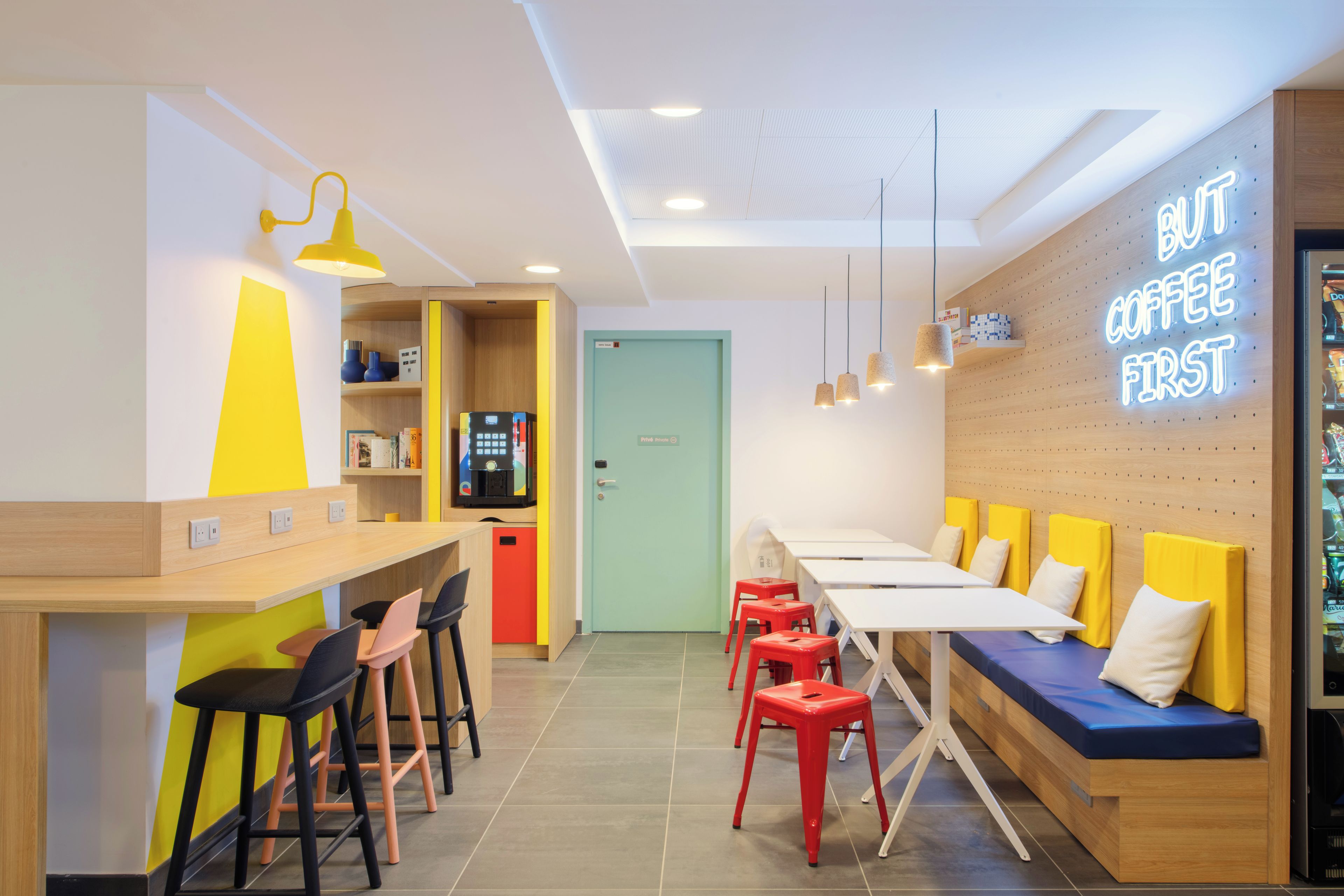 Un interior de cafetería moderna con mostrador, zona de asientos y un letrero de neón.