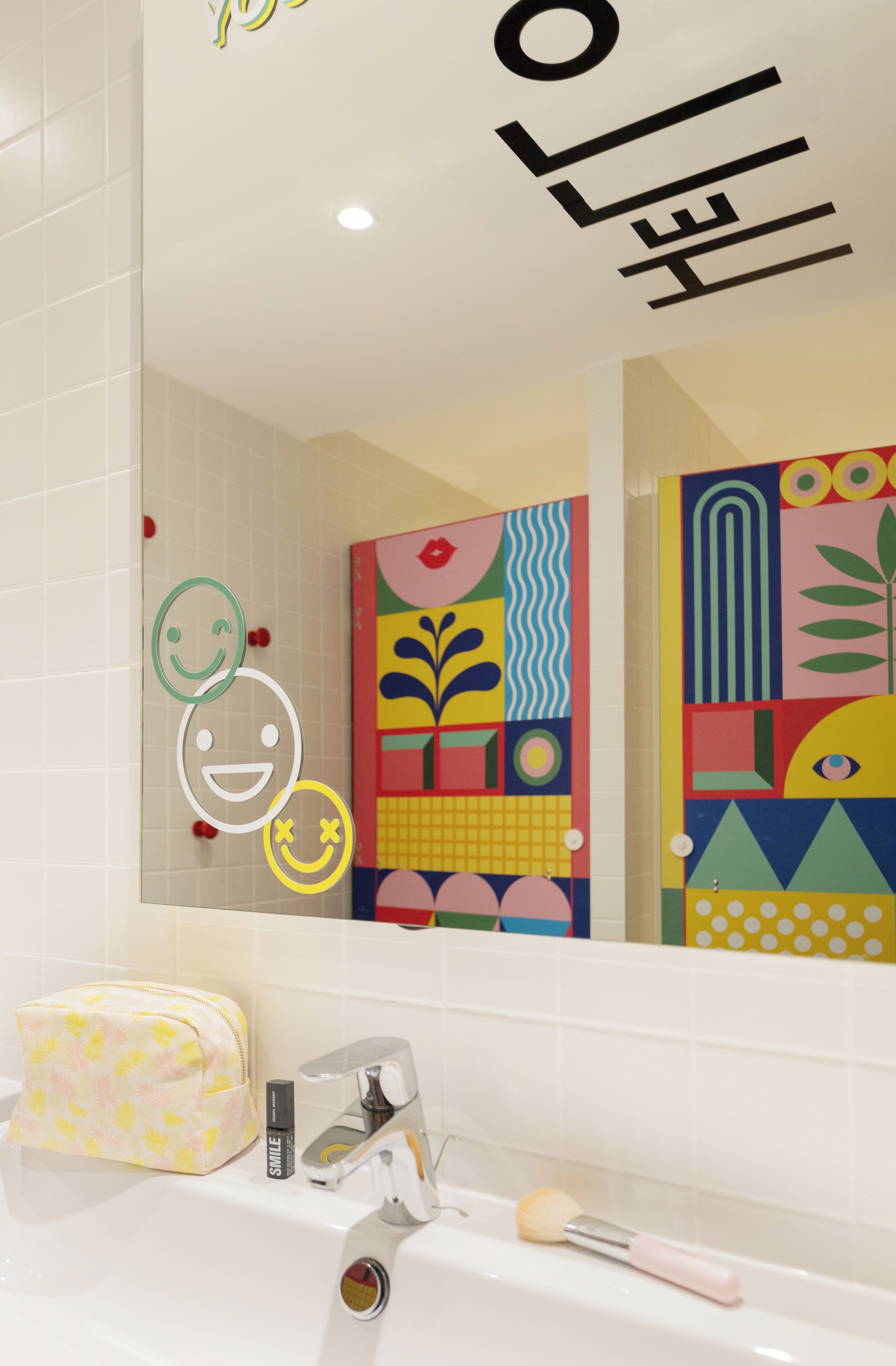 Un baño con un lavamanos blanco, un espejo y una obra de arte abstracta y colorida en la pared.