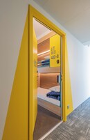 Una puerta amarilla con un letrero que muestra una cama encendida y un número de habitación.