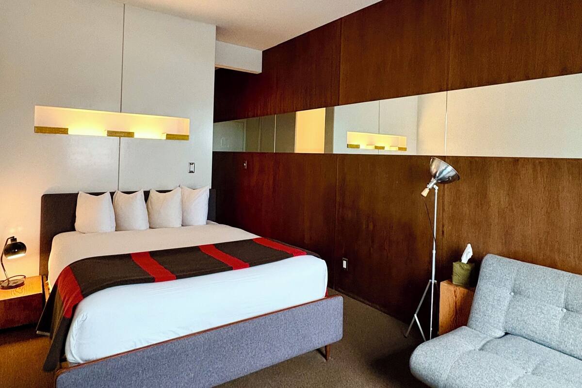 Une chambre d’hôtel moderne avec un grand lit, un canapé et un bureau avec une lampe.