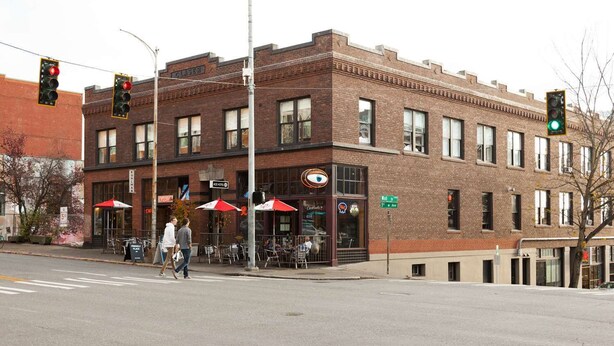 A brick building with a cafe on the ground floor, a visible street sign, and a traffic light. - Ace Hotel Seattle (Seattle)