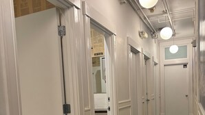 A hotel hallway with white doors, a dark carpet, and exposed pipes on the ceiling. - Ace Hotel Seattle (Seattle)