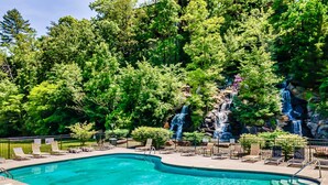 A swimming pool with lounge chairs and a waterfall feature. - Bear Vista Retreat w HotTub Pool View (Sevierville)
