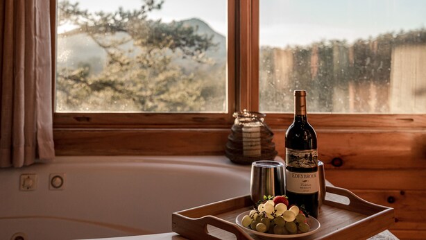 A bottle of Edenbrook Merlot on a wooden tray with a bowl of grapes and a silver canister. - Bear Vista Retreat w HotTub Pool View (Sevierville)
