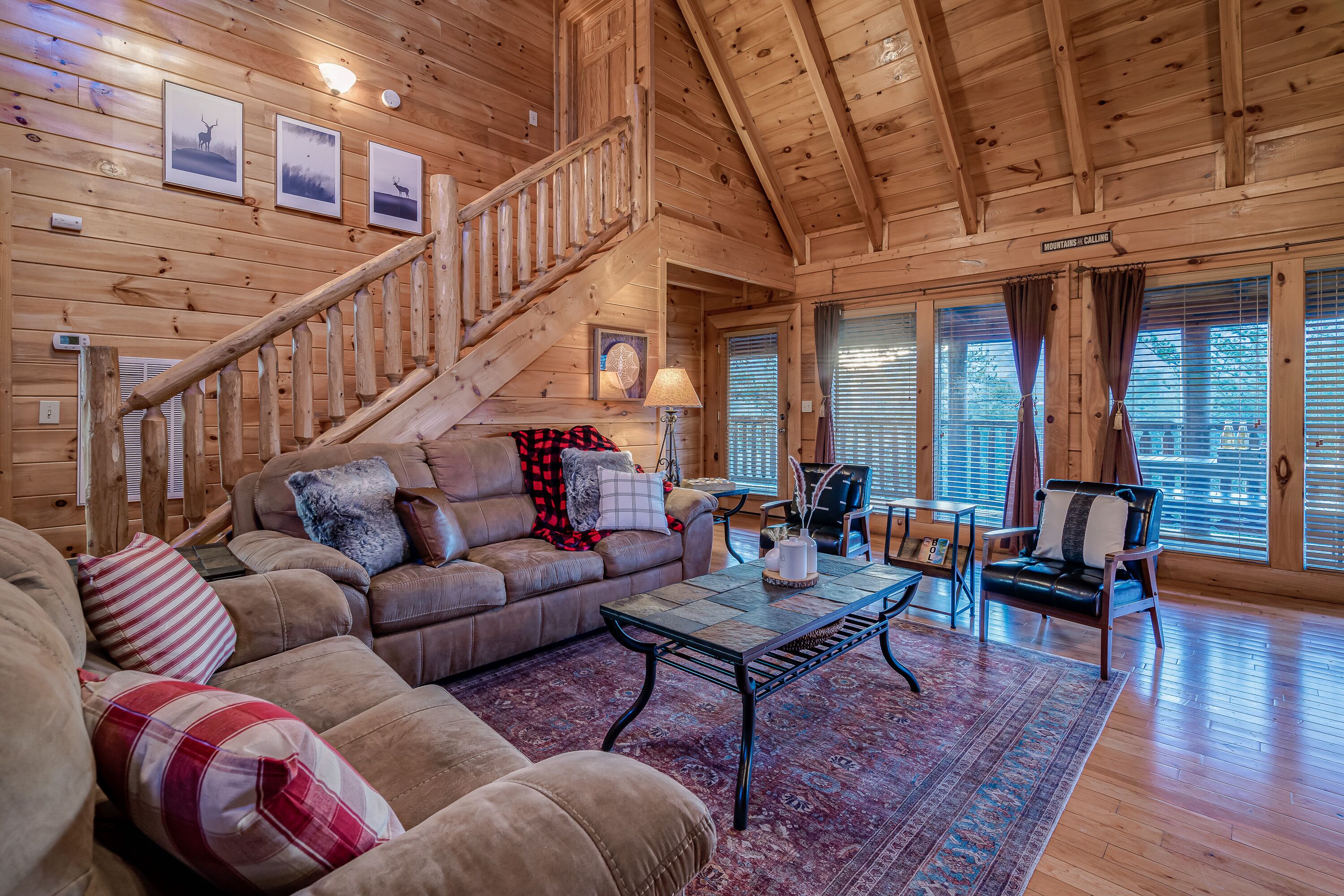 Ein Holzblockbau-Innenraum mit Treppe, Ledersofa und Essbereich.