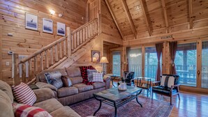 A wooden cabin interior with a staircase, leather sofa, and a dining area. - Bear Vista Retreat w HotTub Pool View (Sevierville)