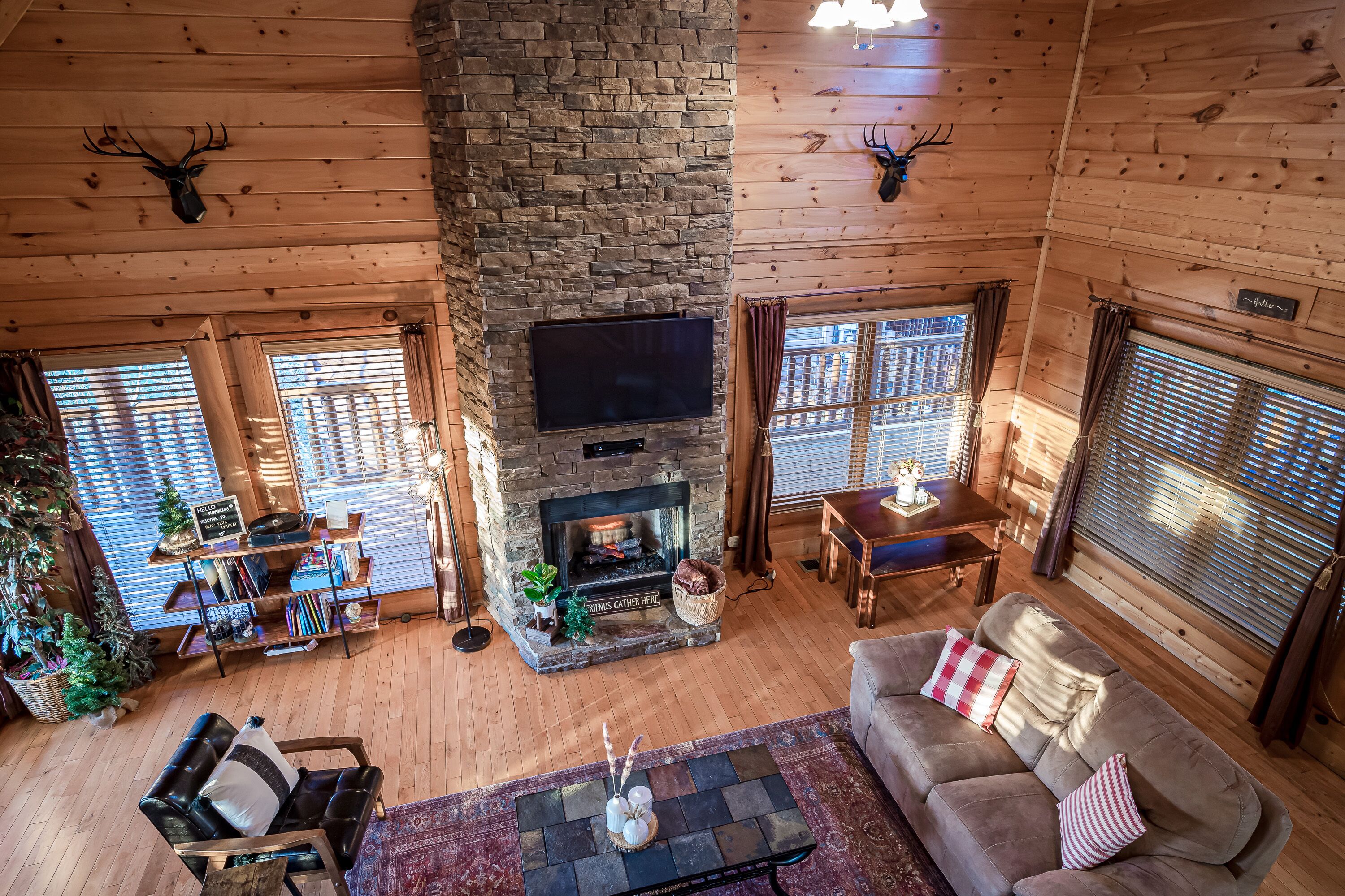 Een gezellig cabin interieur met een stenen open haard, houten wanden, een flatscreen televisie en een comfortabele zithoek.