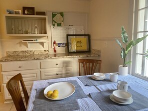 Enjoy meals in this kitchen with a dining table set for a meal, surrounded by modern cabinetry and a granite countertop.