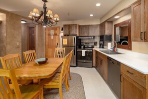 A modern kitchen with wooden cabinets, a stainless steel refrigerator, a built-in oven, and a dishwasher. - Ski-In/Out Condo | Lone Peak Views & Community Pool/Hot Tub (Big Sky)