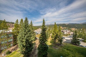 A residential area with modern buildings, a parking lot, and a mountainous backdrop. - Ski-In/Out Condo | Lone Peak Views & Community Pool/Hot Tub (Big Sky)