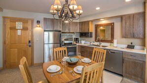 A kitchen with wooden cabinets, a stainless steel refrigerator, a microwave, and a dishwasher. - Ski-In/Out Condo | Lone Peak Views & Community Pool/Hot Tub (Big Sky)