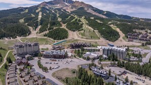 A mountain resort with multiple buildings, a ski lift, and a parking area. - Ski-In/Out Condo | Lone Peak Views & Community Pool/Hot Tub (Big Sky)