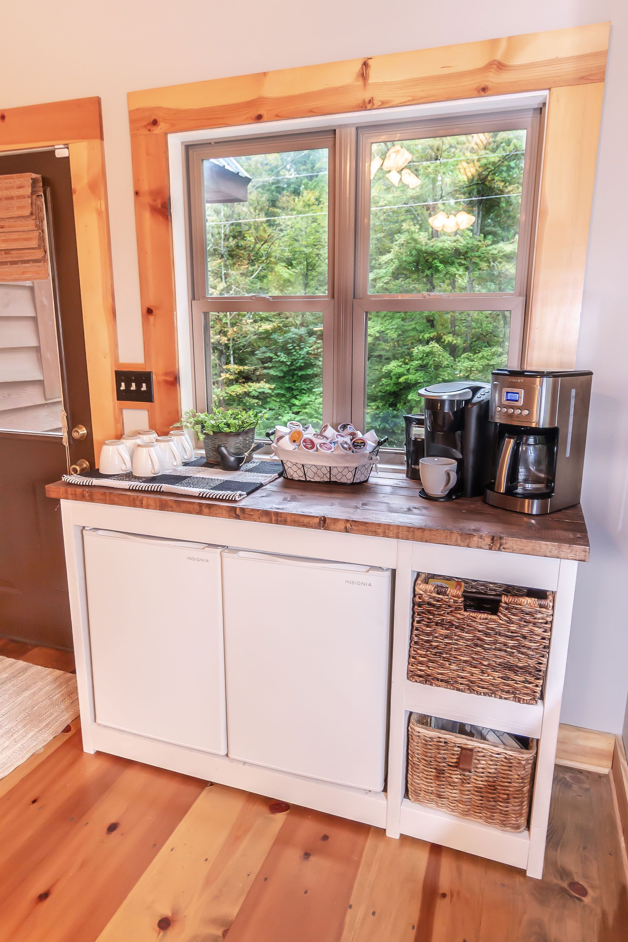 Une petite cuisine avec fenêtre, une machine à café et des paniers de rangement.