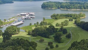 Un campo de golf con un muelle y edificios, rodeado de agua y vegetación.