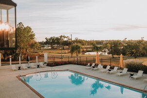 Una piscina con sillones de descanso y vistas a un campo de golf.