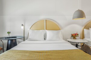 Una habitación de hotel con una cama grande, dos mesitas de noche y una lámpara colgante.