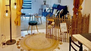 Ett modernt vardagsrum med en blå soffa, en matplats med ett träbord och ett dekorativt bambustaket.