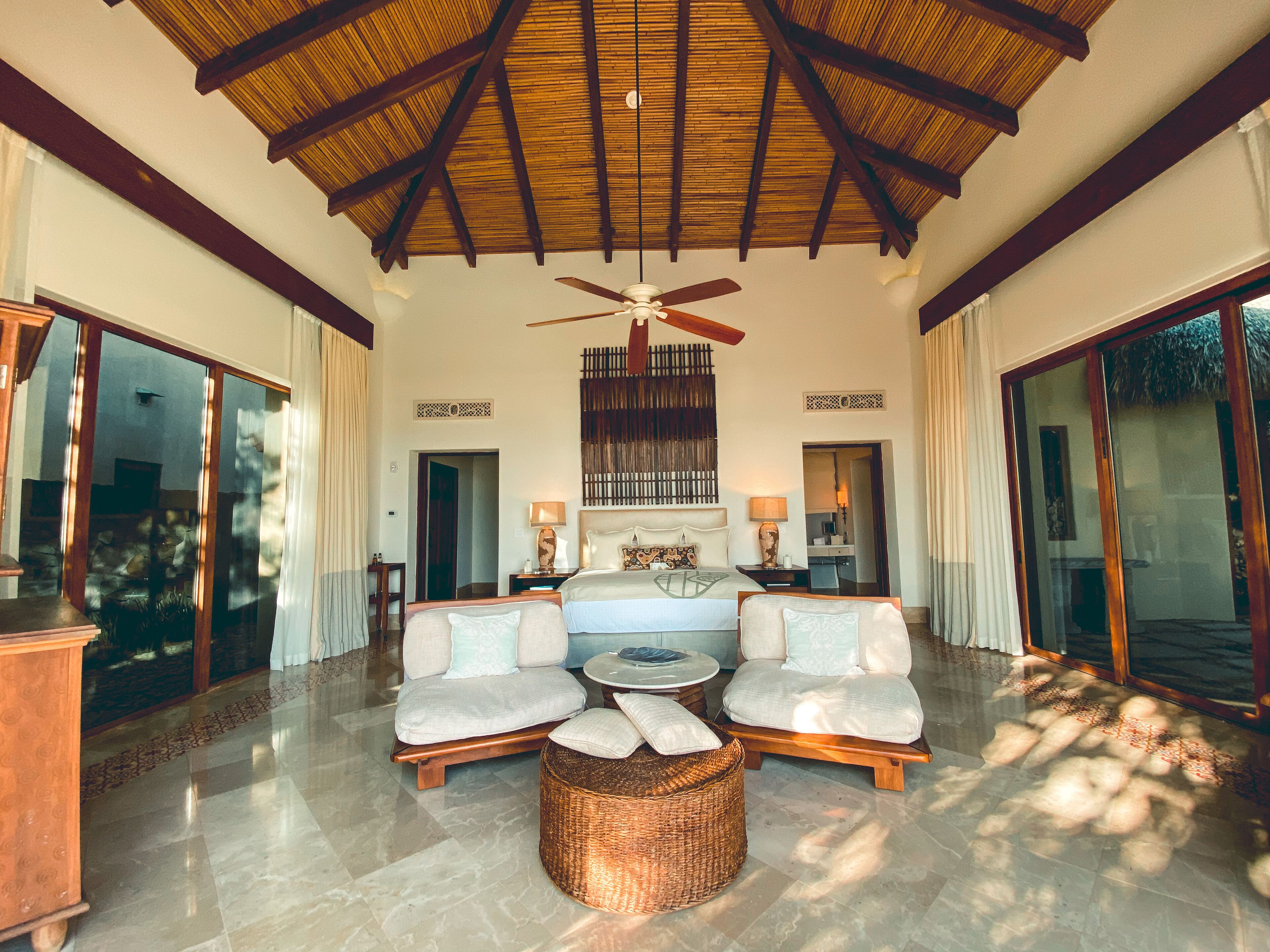 A spacious living area with a high ceiling, a ceiling fan, and a large window providing natural light.