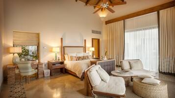 Ein geräumiges Hotelzimmer mit einem großen Bett, zwei Sitzbereichen, einem Schreibtisch und einem Deckenventilator.