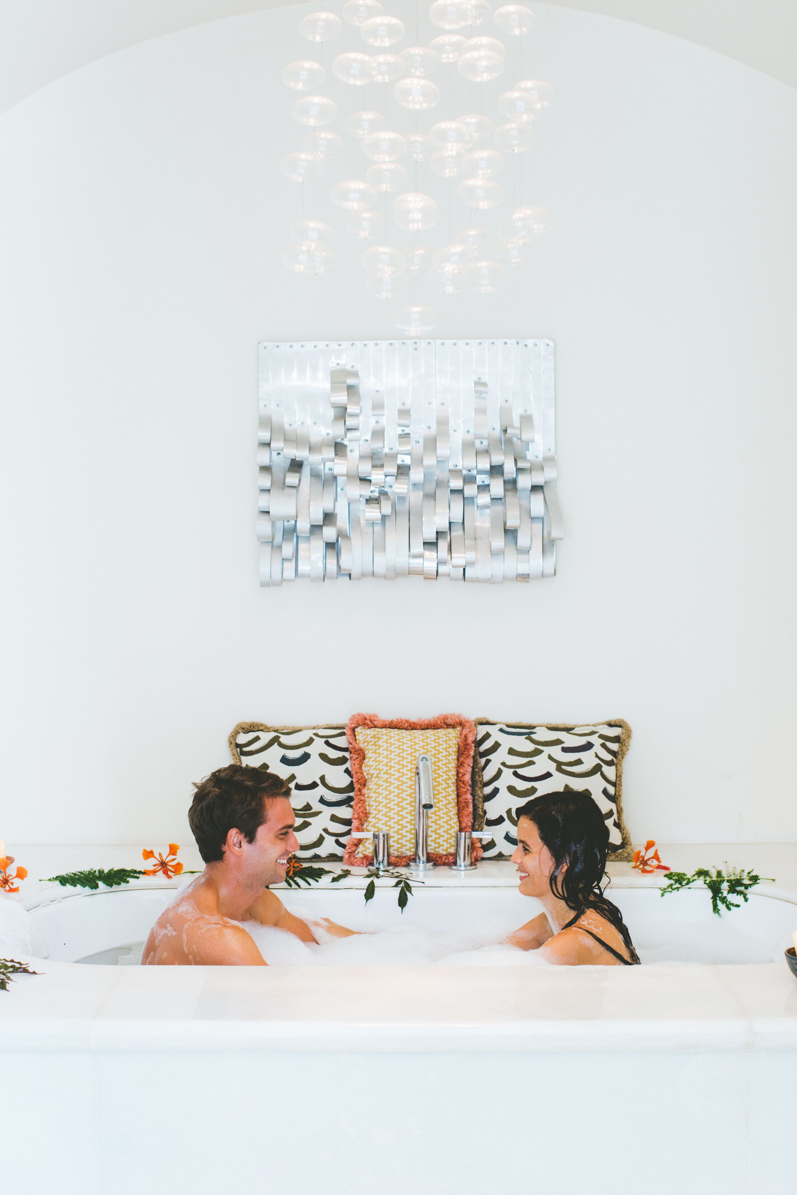 Um casal em uma banheira com um painel decorativo na parede.