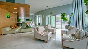 Un hall d’entrée moderne avec un canapé beige, deux fauteuils, une table basse et une plante en pot.