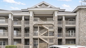 A multi-story building with a stone facade, balconies, and a central staircase. - Family Getaway • Spacious 3BR Condo • Resort Amenities + Perks (Branson)