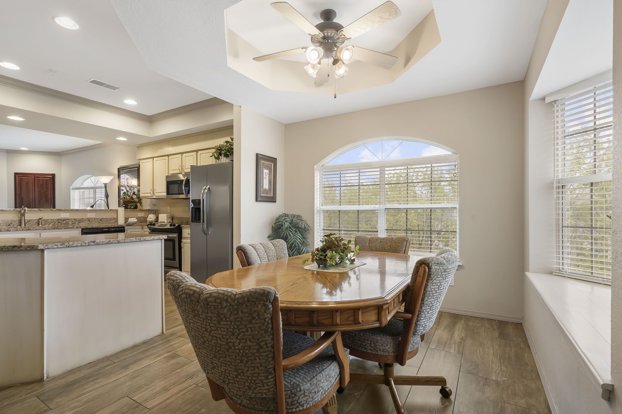 A modern kitchen with a central island, built-in appliances, and a dining area with a round table and chairs.