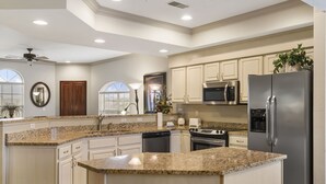 Uma cozinha moderna com bancadas de granito, eletrodomésticos de aço inoxidável e armários brancos.