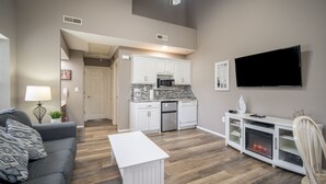 Een moderne woonkamer met een grijze bank, een witte salontafel en een entertainmentmeubel met openhaard.