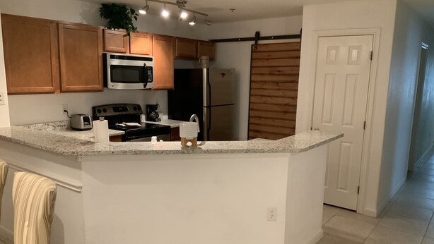 A kitchen with wooden cabinets, a microwave, a stove, and a refrigerator. - Amazing, Contemporary, Beautiful, Peaceful, and Perfectly Located Property (San Antonio)