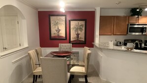 A dining area with a glass table, four chairs, and two framed paintings on the wall. - Amazing, Contemporary, Beautiful, Peaceful, and Perfectly Located Property (San Antonio)