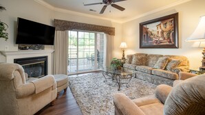 Una sala de estar con chimenea, televisor, sofá, mesa de centro y un cuadro en la pared.
