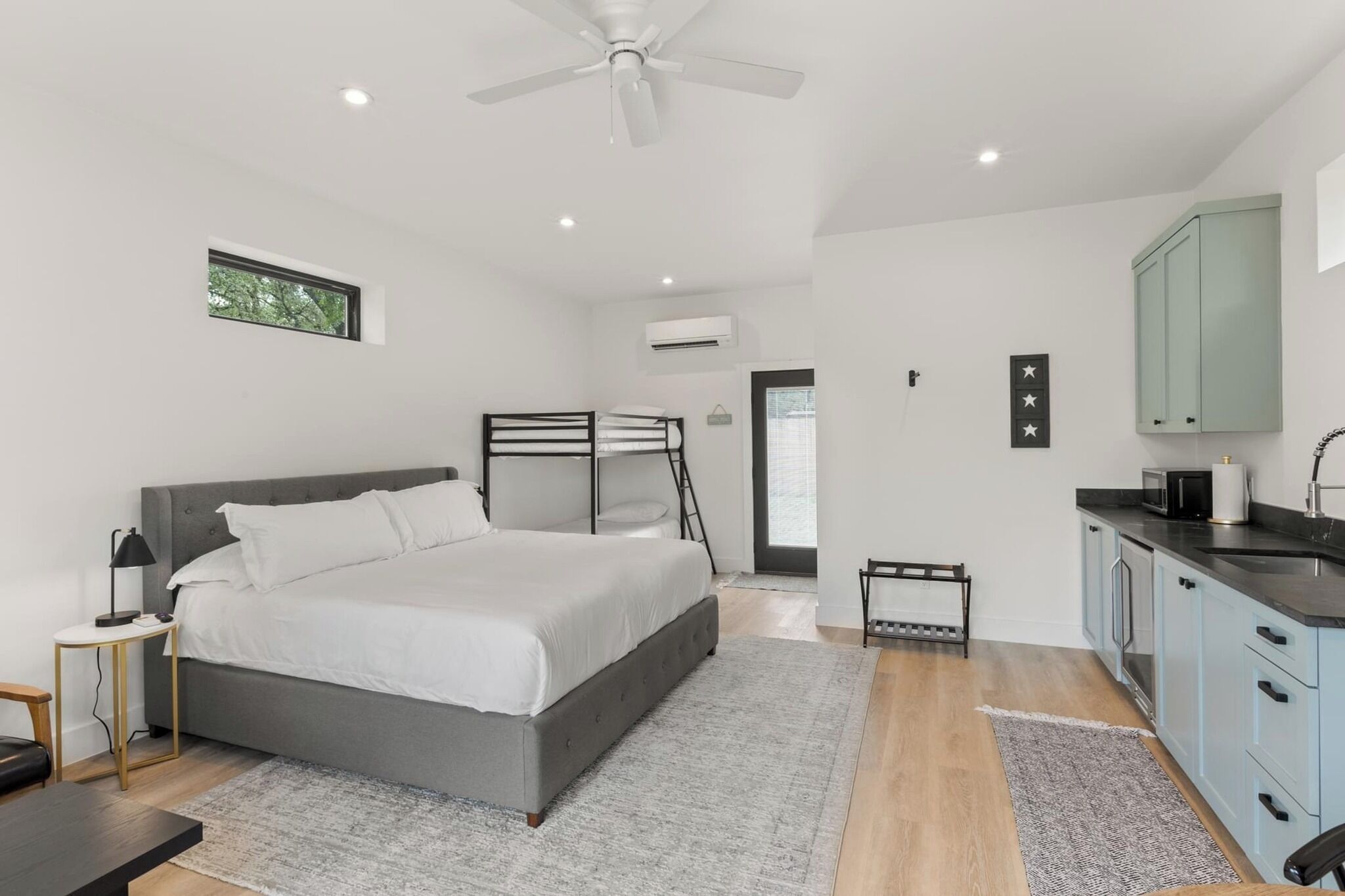 Une chambre moderne avec un grand lit, des tables de chevet, un ventilateur de plafond et une petite fenêtre.