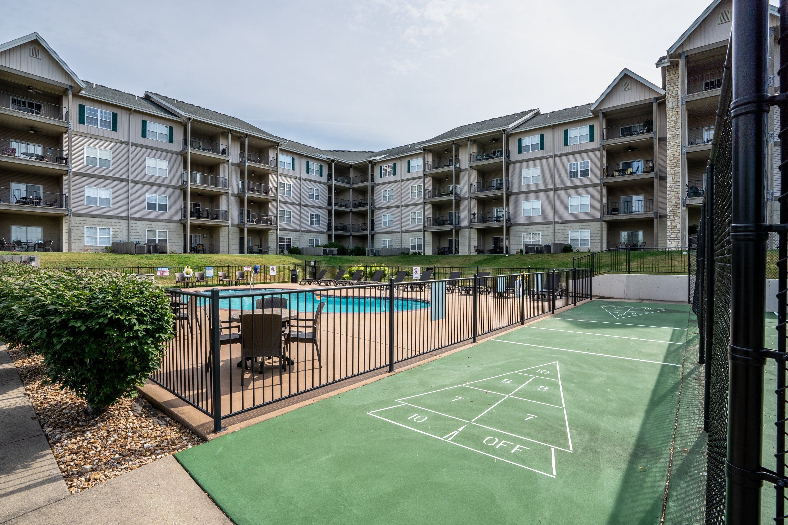 A multi-story residential building with a rooftop pool and a shuffleboard court.