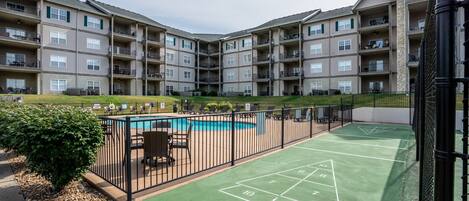 A multi-story residential building with a rooftop pool and a shuffleboard court.