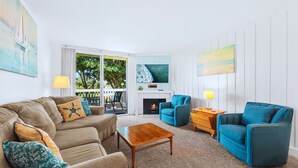 A living room with a beige sofa, a blue armchair, a wooden coffee table, and a fireplace.