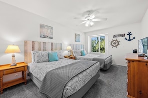 A bedroom with two beds, a ceiling fan, and nautical-themed decor.
