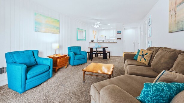 A living room with a sofa, armchairs, a coffee table, and a dining area with a table and chairs.