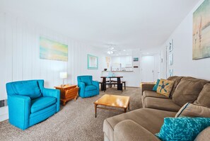 A living room with a sofa, armchairs, a coffee table, and a dining area with a table and chairs.