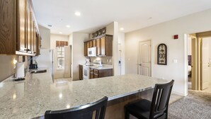 A kitchen with granite countertops, wooden cabinets, and a central island with bar stools. - 2 Bedroom, 2 Bathroom Walk-in Golf Condo with Private, Covered Balcony (Branson)