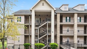 A multi-story apartment building with a central staircase, balconies, and a stone facade. - 2 Bedroom, 2 Bathroom Walk-in Golf Condo with Private, Covered Balcony (Branson)