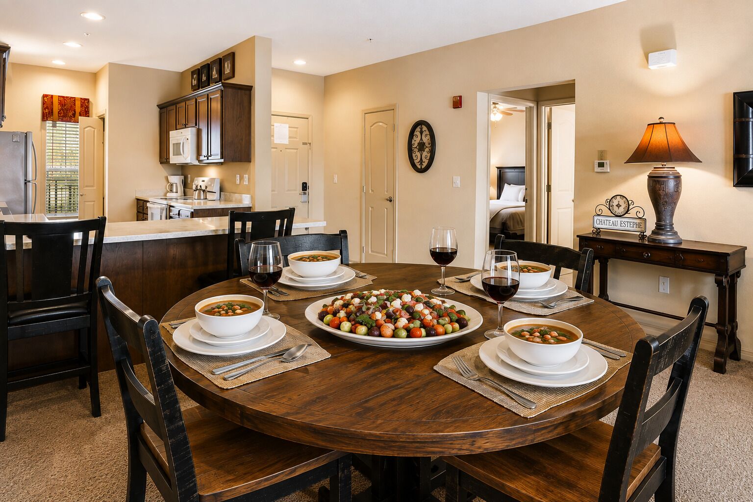 A dining area with a round table, chairs, and a variety of dishes including soup and a salad.