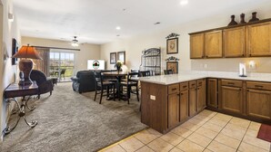 A spacious kitchen with wooden cabinets, a large island, and a dining area with a table and chairs. - 2 Bedroom, 2 Bathroom Walk-in Golf Condo with Private, Covered Balcony (Branson)