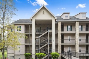 A multi-story building with a central staircase, balconies, and a stone facade. - Spacious 2-Bedroom Golf Condo in hte Heart of Branson (Branson)