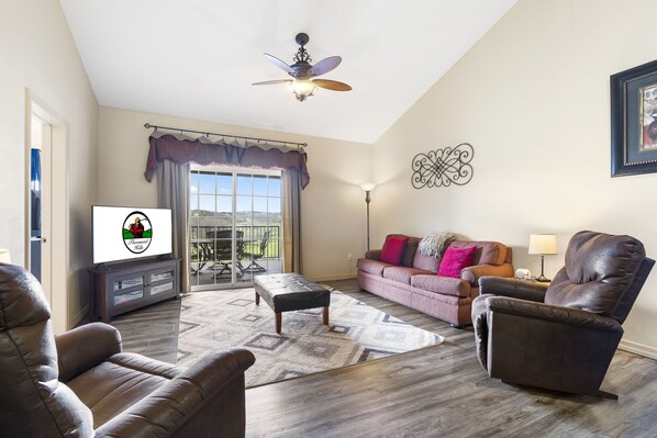 A living room with a sofa, armchair, ottoman, and a ceiling fan. - Spacious 2-Bedroom Golf Condo in hte Heart of Branson (Branson)