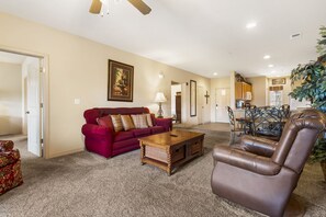 A living room with a red sofa, a brown leather chair, a wooden coffee table, and a dining area with a metal table and chairs.