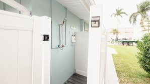 Een smalle gang met een lichtblauwe muur, een witte deur en een klein raam.