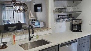 Une cuisine moderne dotée d’un îlot central, d’un lave-vaisselle encastré et d’un grand miroir au-dessus de l’évier.